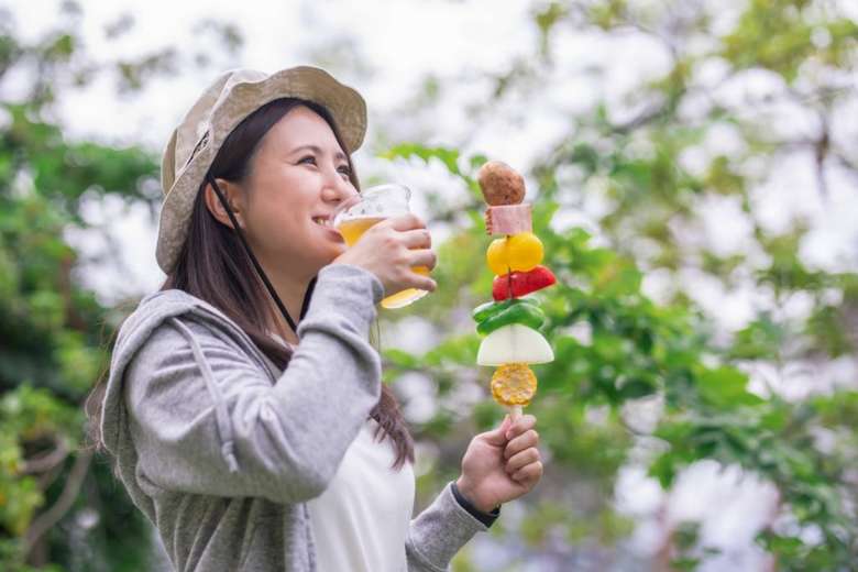 ビールを片手にバーベキュー肉を持つ女性