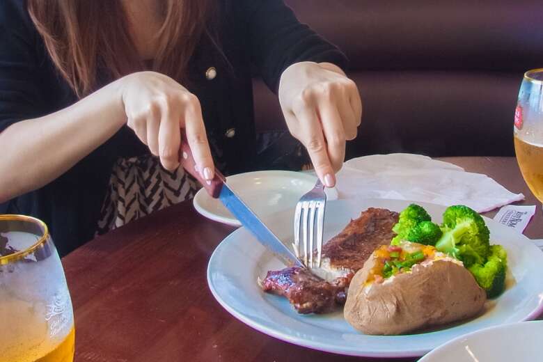 ステーキ肉をナイフでカットする女性